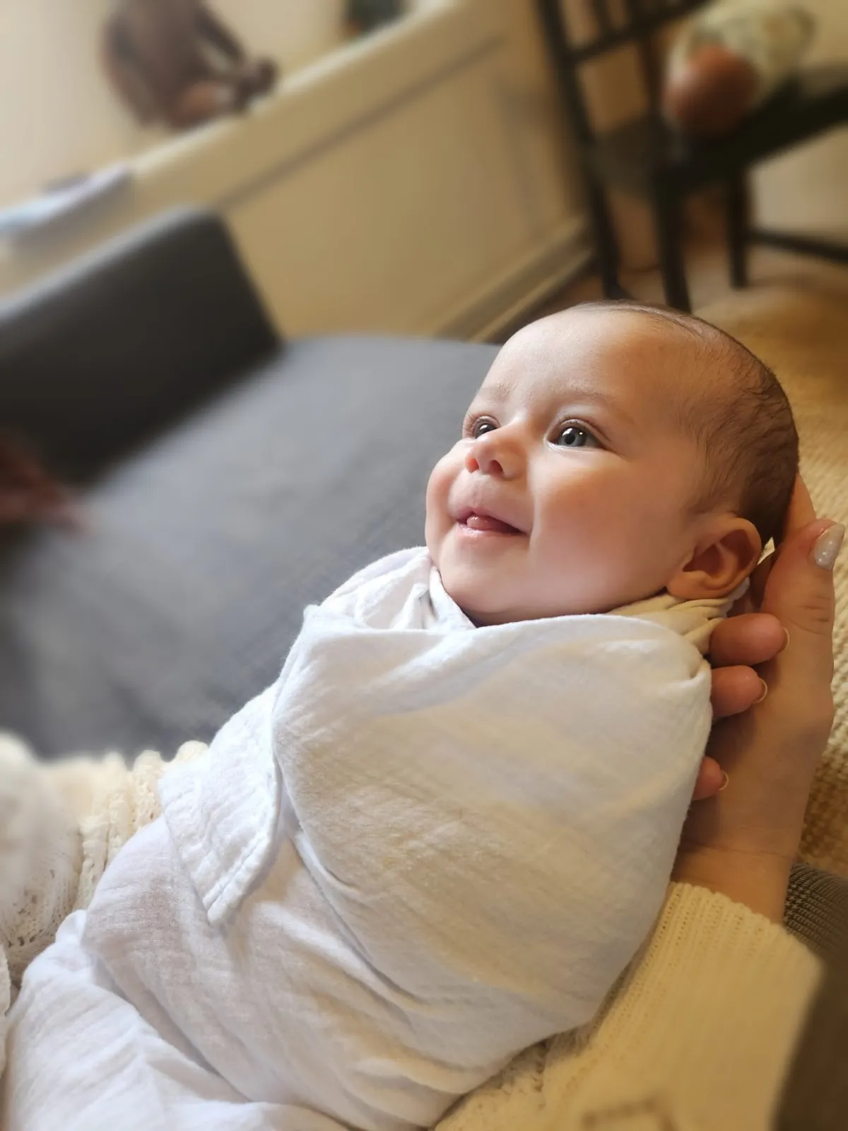 Bébé emmailloté souriant après un rituel du bain sensoriel
